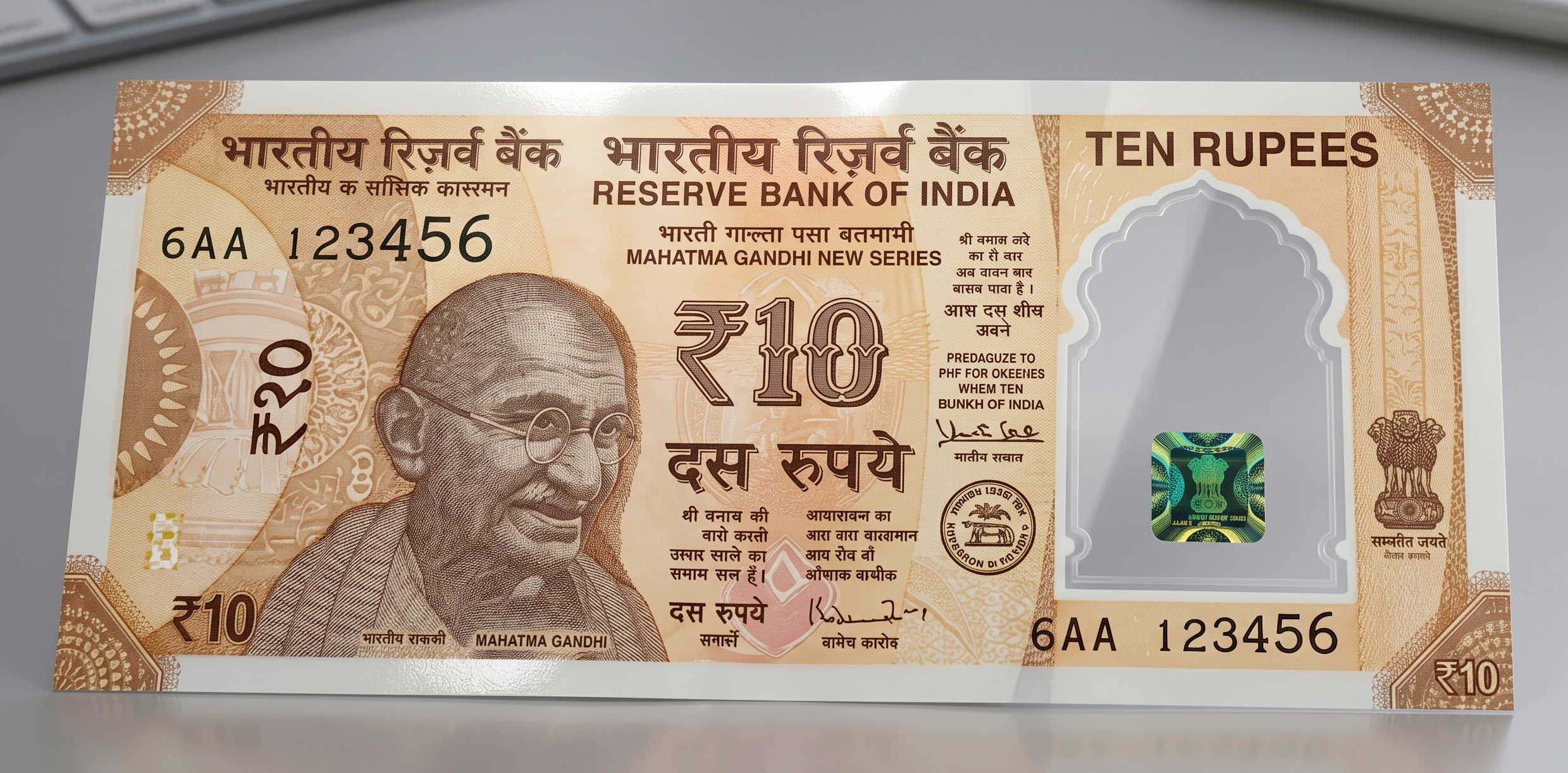 A realistic concept design of the Reserve Bank of India (RBI) new ₹10 polymer plastic currency note, featuring Mahatma Gandhi and a prominent translucent, transparent security window with a holographic emblem, displayed flat on a clean, modern grey office desk.